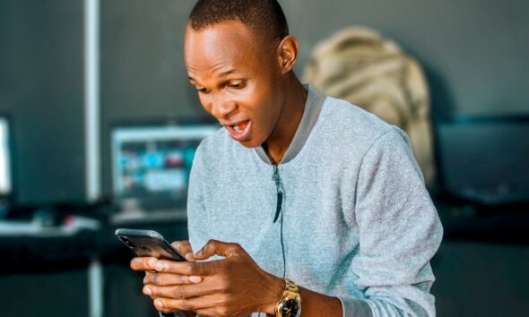 a man looking at his cell phone and laughing