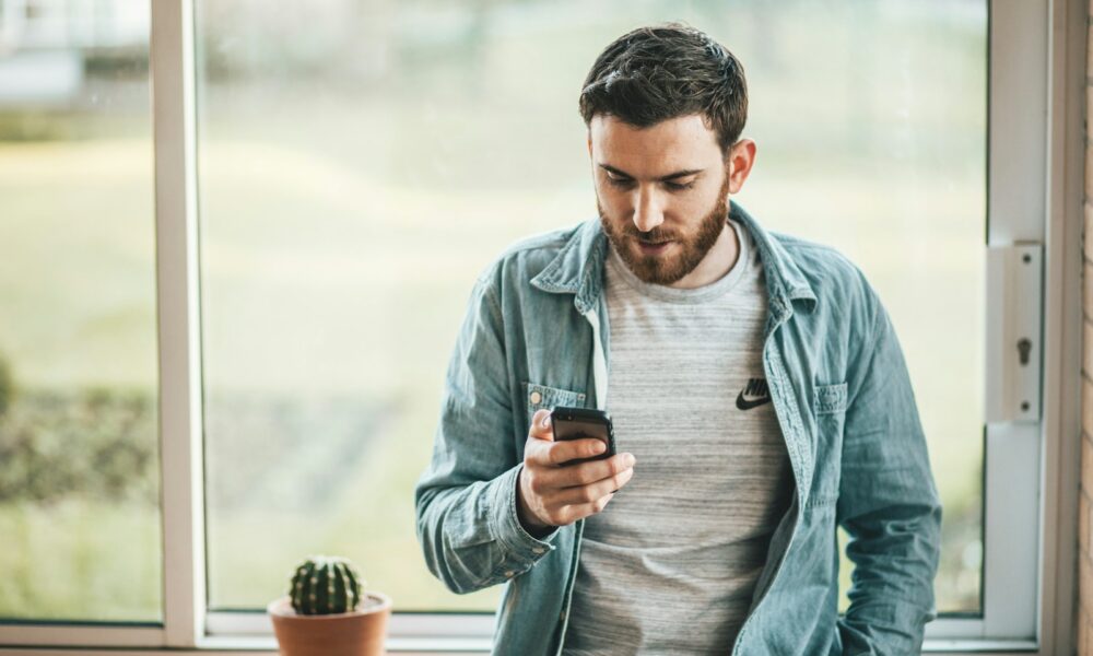 man holding a smartphone near the window